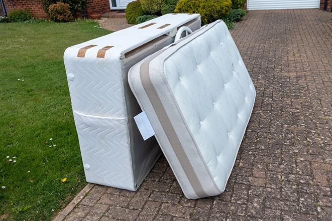 two people dragging a used mattress to the curb